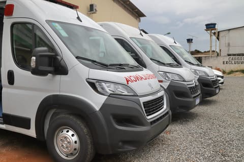 Fila de ambulâncias brancas novas estacionadas em um pátio.