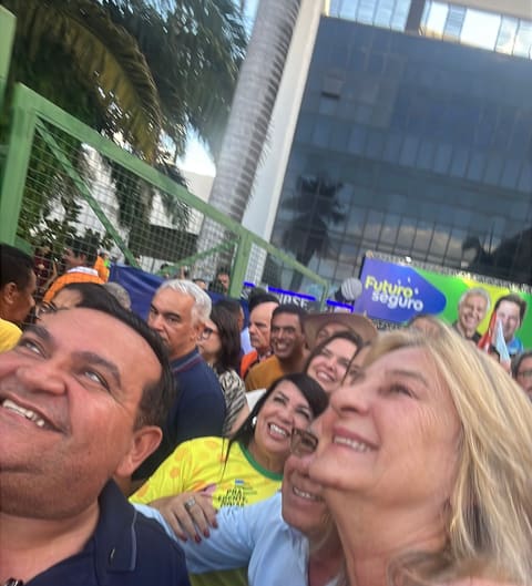 Dra. Zeli abraçada a um apoiador, sorrindo, em meio à multidão de uma agenda de campanha.