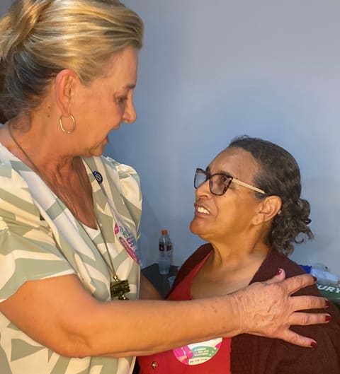Dra. Zeli abraça uma moradora sorridente durante um encontro.