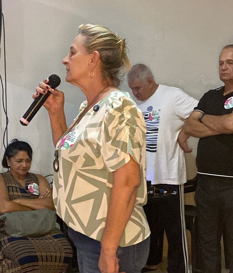 Dra. Zeli fala ao microfone diante de moradores em uma reunião comunitária.