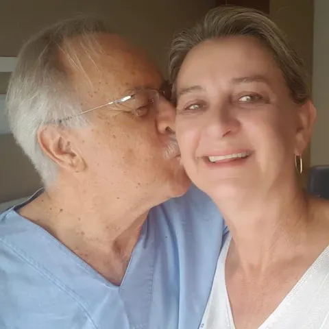 Adjacy beija o rosto de Zeli, que sorri, em uma foto caseira.