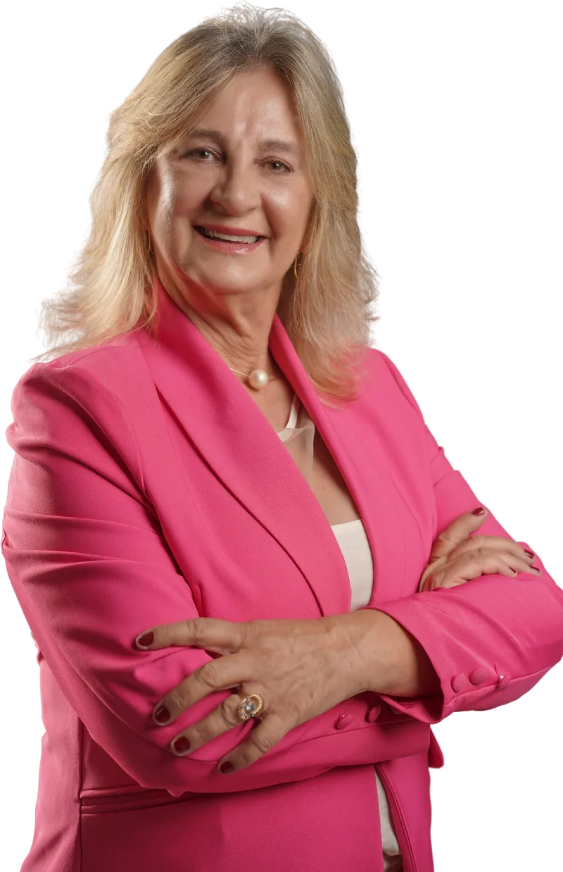 Dra. Zeli, de blazer rosa, sorrindo com os braços cruzados.